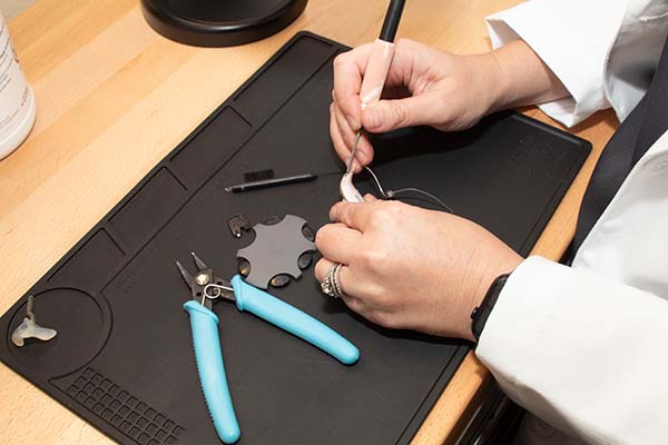 Audiologist is repairing a hearing aid.