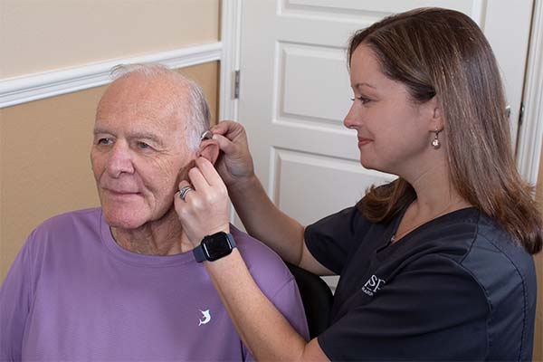 Provider placing a hearing aid on a patient.